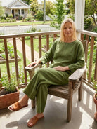 woman wearing loose solid color two-piece set sitting on wooden chair outdoors