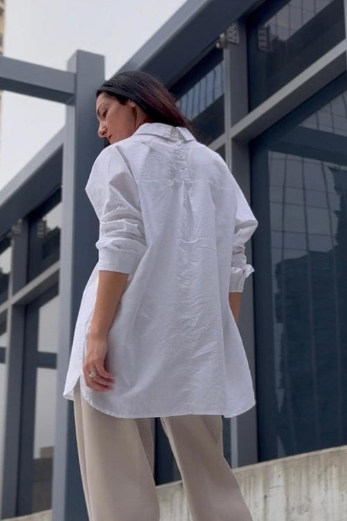 Woman wearing oversized white linen cotton blend shirt with loose sleeves and gathered back detail outdoors