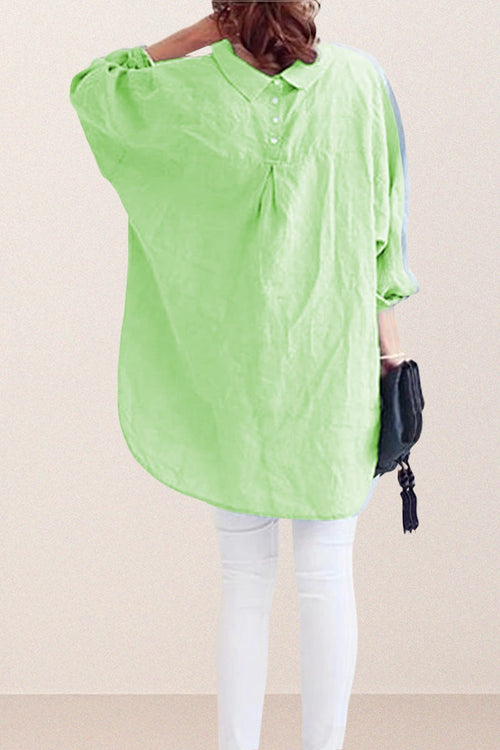 Back view of oversized linen shirt in light green with loose sleeves and buttoned back detail worn with white pants and black handbag