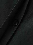 Close-up of oversized 100% cotton black shirt fabric with button detail