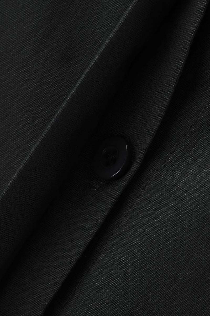 Close-up of oversized 100% cotton black shirt fabric with button detail