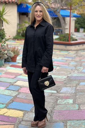 Woman wearing oversized 100% cotton black shirt and wide-leg pants co-ord set outdoors with handbag