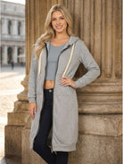 Woman wearing oversized long zip sweatshirt hoodie in gray with a drawstring hood and large front pockets