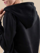 woman wearing black oversized long zip sweatshirt hoodie with hood up back view