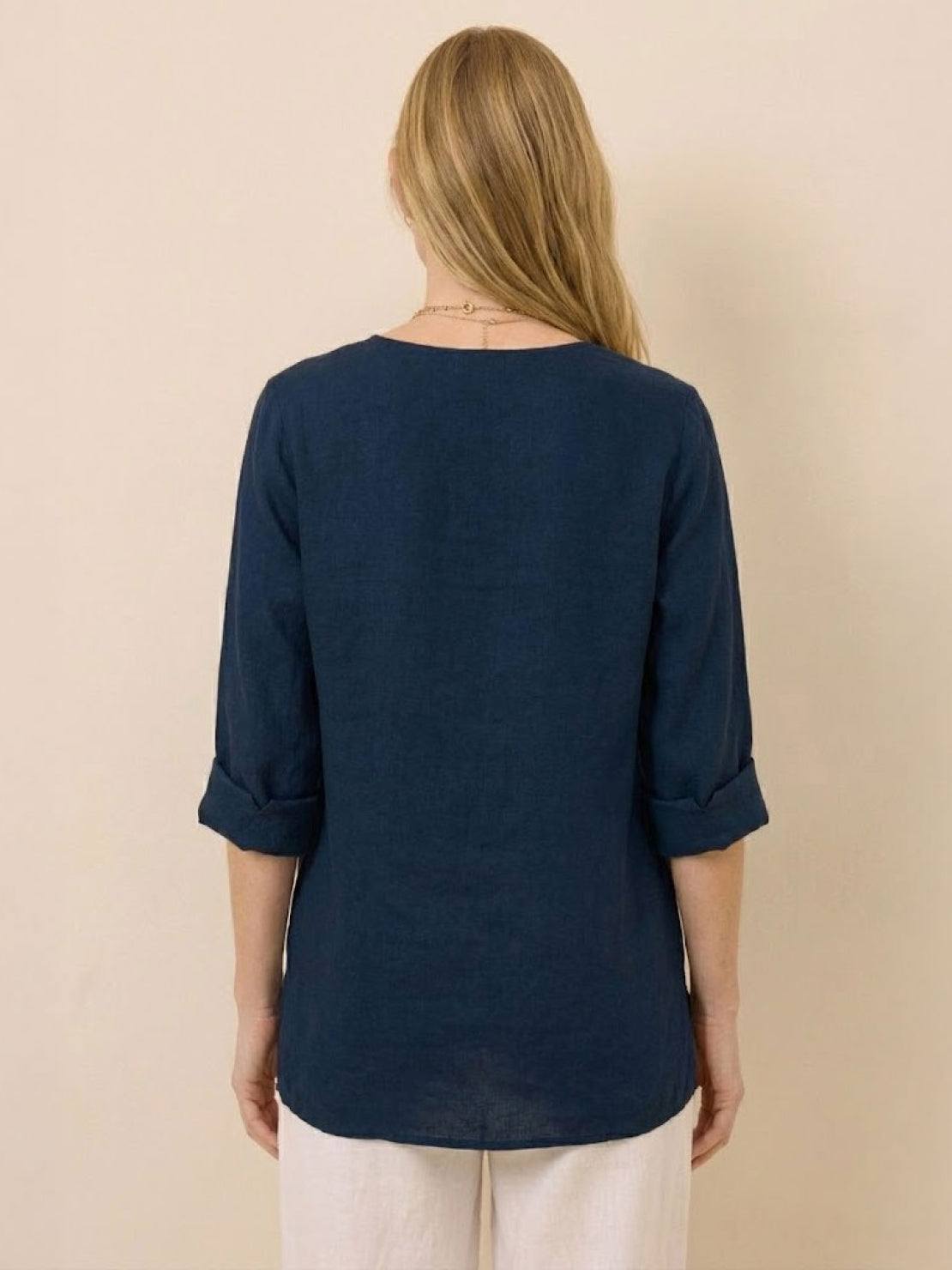 Back view of woman wearing navy blue pure linen age-defying button detail shirt with rolled sleeves