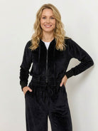 Woman wearing a modern cropped velour hoodie and high-waist velour tracksuit pants in vibrant color