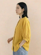 woman wearing relaxed loose breathable linen yellow blouse with rolled sleeves and front buttons