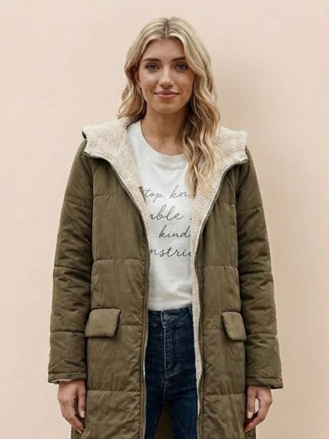 Woman wearing olive green sherpa-lined hooded teddy coat with front pockets and zip closure