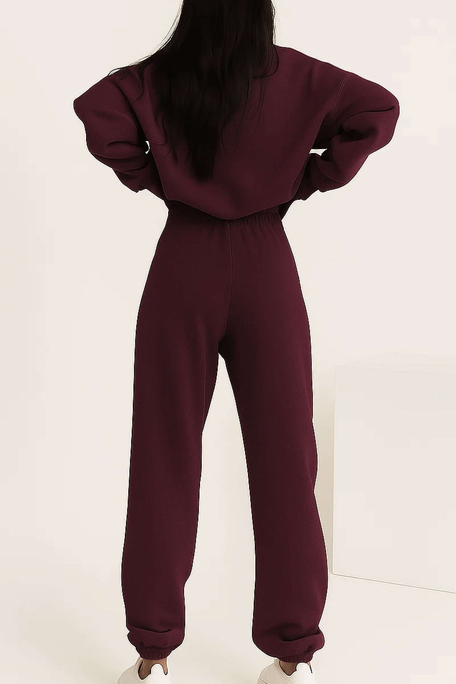 Back view of woman wearing a burgundy cotton blend tracksuit with stretch waistband and cuffs.