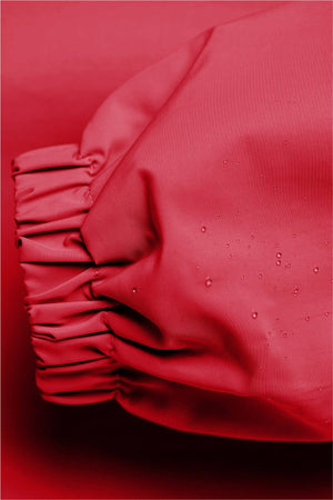 Close-up of red Rain Couture Windbreaker sleeve with water-resistant fabric and elastic cuff detailing.
