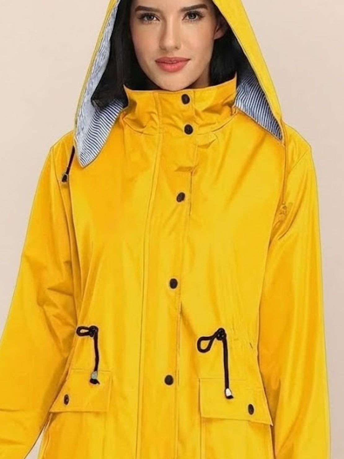 Woman wearing yellow water resistant hooded striped windbreaker jacket with adjustable waist and multiple pockets