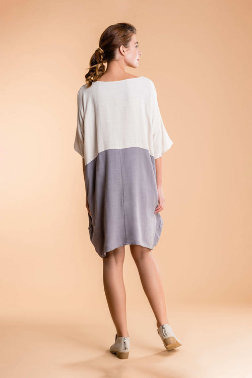 Back view of a woman wearing a loose fit oversized T-shirt dress in color block with white and gray shades.